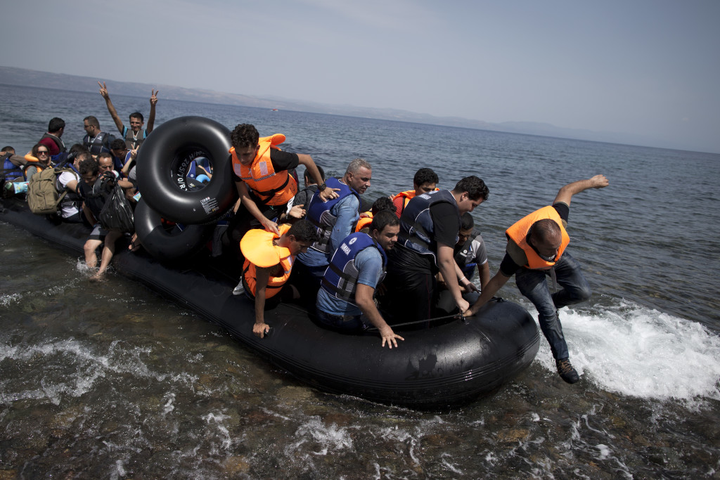 Syrian men, women and children arrive aboard a dinghy after crossing from Turkey, on the island of Lesbos, Greece, Monday, Sept. 7, 2015. The island of some 100,000 residents has been transformed by the sudden new population of some 20,000 refugees and migrants, mostly from Syria, Iraq and Afghanistan. (AP Photo/Petros Giannakouris)