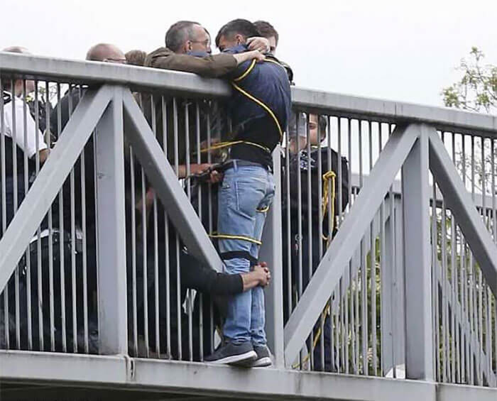 People Holding Onto Man Trying To Commit Suicide